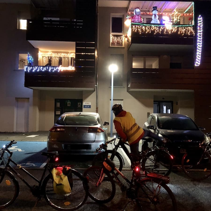 une cycliste devant une maison illuminée